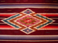 Mexican vintage textiles, a Saltillo sarape, c. 1940. Beautiful burgundy background. Made of very finely woven wool with silk in the center medallion and decorative side-bars.  Closeup of center medallion.