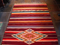 Mexican vintage textiles, a Saltillo sarape, c. 1940. Beautiful burgundy background. Made of very finely woven wool with silk in the center medallion and decorative side-bars.  A photo showing most of the saltillo.