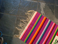 Mexican vintage textiles and sarapes, a textile or sarape woven of fine wool and representing the Mexican flag and national symbol of the eagle with snake, c. 1940. The piece bears the traditional colors of the Mexican flag: red, green, and white. Photo showing one edge of the Saltillo sarap with fringe intact.