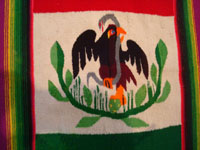 Mexican vintage textiles and sarapes, a textile or sarape woven of fine wool and representing the Mexican flag and national symbol of the eagle with snake, c. 1940. The piece bears the traditional colors of the Mexican flag: red, green, and white. Another closeup of the eagle on the Saltillo sarape.