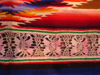 II-11: Mexican vintage textiles and sarapes, a spectacular Saltillo sarape with bands of tela deshilada (threads are removed and lovely flowers are then created with the remaining threads), c. 1920-40. This is an extremely rare and beautiful Mexican textile. It is museum- quality and very rare. Colors are brilliant and the center medallion is incredible! Condition is excellent. This piece was highly treasured and very well cared for by the original collector(s). Size: 70 inches long with fringes (56 inches long not including fringes) by 29 inches wide. Price: $2200.