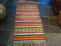 II-11: Mexican vintage textiles and sarapes, a spectacular Saltillo sarape with bands of tela deshilada (threads are removed and lovely flowers are then created with the remaining threads), c. 1920-40. This is an extremely rare and beautiful Mexican textile. It is museum- quality and very rare. Colors are brilliant and the center medallion is incredible! Condition is excellent. This piece was highly treasured and very well cared for by the original collector(s). Size: 70 inches long with fringes (56 inches long not including fringes) by 29 inches wide. Price: $2200. Another view of the entire sarape.