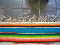 Mexican vintage textiles and sarapes, a beautiful Saltillo sarape with a turquoise background and wonderful center medallion, c. 1940. A closeup of one edge of the sarape showing the fringe.