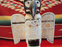 Native American Indian antique folk art, a carved, bone totem pole from Alaska, c. 1920-30's. The figure of the Raven with outstretched wings (the mythical hero of the Tlingit) hovers at the top of the pole, sheltering the three children of the sun. Photo of the Raven at the top of the pole.