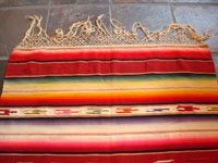 Mexican vintage sarapes and textiles, an incredible Saltillo sarape with a beautiful center medallion, c. 1930's. The predominant color of this multi-colored piece is a beautiful red. Photo showing one end of the Saltillo sarape with its fringe intact.