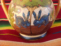 Mexican vintage pottery and ceramics, a lidded jar with handles from Tlaquepaque, Jalisco, c. 1930's. The lidded jar has the petatillo hatch-work pattern in the background, and features two wonderful blue bunnies amidst foliage on both the front and the back. Closeup of bunnies on front side of jar.