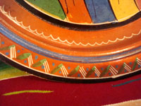 Mexican vintage pottery and ceramics, a wonderful charger from Tlaquepaque, c. 1930-40. Beautifully decorated with a Diego Rivera-like scene of a woman kneeling as she contemplates lovely flowers. Closeup photo of the rim of the charger.