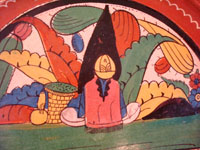 Mexican vintage pottery and ceramics, a wonderful charger from Tlaquepaque, c. 1930-40. Beautifully decorated with a Diego Rivera-like scene of a woman kneeling as she contemplates lovely flowers. Closeup photo of the kneeling woman.