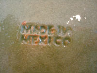 Closeup photo showing the signature stamped on the back of the Tlaquepaque plate with pale green background.