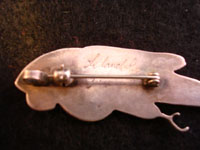 A closeup photo of the back of the Zuni parrot pin/pendant, showing signature.