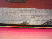 Closeup of the text on the front of the vintage Mexican exvoto on tin.