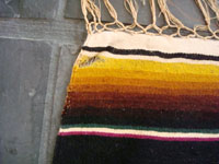 A closeup photo of the vintage Mexican textile, a Saltillo sarape, showing a very small hole.
