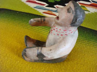 Native American Indian pottery or folk art, a storyteller attributed to Demasia Cordero, sister of the famous potter, Helen Cordero, and also famous in her own rite, c. 1940.  A photo giving a side-view of the piece.