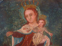 Mexican vintage devotional art and folk art, a retablo on tin depicting Our Lady of Mt. Carmel of the Scapulars, holding the Infant Jesus wearing his crown, c. 1900. Closeup photo of Our Lady's face.