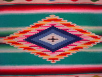 Mexican vintage textiles and sarapes, a wonderful Saltillo sarape with a fine center diamond, c. 1920. The center diamond and the decorative side-bars contain very fine silk. Closeup photo of the center medallion of the sarape.