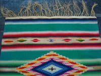 Mexican vintage textiles and sarapes, a wonderful Saltillo sarape with a fine center diamond, c. 1920. The center diamond and the decorative side-bars contain very fine silk. Photo of one end, showing the wonderful fringe still fully intact.