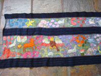 Mexican vintage textiles and sarapes, a beautifully woven and embroidered woman's skirt, Guerrero, 1940's. The long skirt, made to be wound around the waist and secured with a belt, is embroidered with wonderful animals, plants, and figures. Closeup photo of embroidered animals and plants.