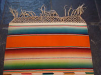 Mexican vintage textiles and sarapes, a lovely Saltillo sarape runner with a wonderful center design, c. 1940. Very beautifully woven of fine wool with silk in the center medallion and decorative side-bars. Photo showing the fringe at one end.