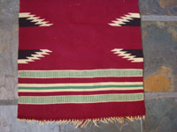 New Mexican vintage textile, a weaving from Chimayo, New Mexico, c. 1930's. The textile has a very deep burgundy background, and the colors are bright and very beautiful.  Closeup of one side of the textile.