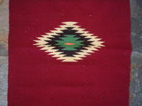 New Mexican vintage textile, a weaving from Chimayo, New Mexico, c. 1930's. The textile has a very deep burgundy background, and the colors are bright and very beautiful.  Closeup photo of the denter diamond of the textile.