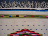 Mexican vintage textiles and sarapes, a Saltillo sarape with a white background and a very fine silk center-medallion and decorative side-bars, c. 1920's. Very beautifully woven with the fine fringe intact at both ends. Photo showing the fringe at one end of the saltillo sarape.