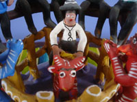Mexican vintage folk art, a wonderful Ocumicho pottery scene of a lively rodeo, complete with a bull-rider, musicians, and fans, Ocumicho, Michoacan, c. 1980's. Closeup photo of the bull rider and bull.