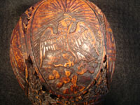 Mexican vintage folk art, a finely carved coconut with scenes from the Mexican Revolution of 1910, c. 1925-35. The carved coconut has the Mexican national emblem of the eagle and snake inlaid in abalone. Closup photo of Mexican eagle.