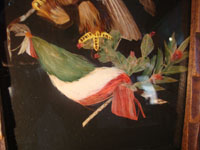 Mexican vintage folk art, a feather-work picture of an eagle with the Mexican flag, c. 1920. This picture of the eagle with the Mexican flag is done with hundreds of tiny feathers of many colors. Featherwork pictures are a wonderful artform originating in Mexico in pre-Hispanic times. Closeup of eagle showing Mexican flag.