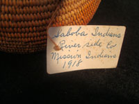 Native American Indian antique basket, Mission basket with original sales tag, 1918. Very finely woven Mission basket with the original sales tag from c. 1918. Various shades of juncus on a deer grass bundle; very tightly coiled. The original sales tag identifies this basket as from the Saboba Reservation, Riverside, California, 1918. The other side of the tag identifies the basket as coming from a Marvin Whitaker of Portland, Oregon, the dealer or original collector. Condition is excellent. Photo of the original sales tag from this Mission Indian basket.