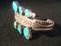 Native American Indian vintage silver jewelry, a Navajo sterling silver bracelet with 6 beautiful turquoise stones, c. 1920. Made from ingot silver, with wonderful early stamping and file marks. This is a treasure for the collector of Native American Indian jewelry! Photo of bracelet from one side.