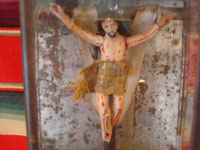 Mexican vintage devotional art, a carved wooden figure of the crucified Christ in a tinwork and glass nicho, c. 1920. The wood carving is covered with gezzo and very beautifully painted. A closeup photo of the retablo of the Crucifixion.