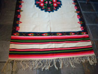 Mexican vintage textiles and sarapes, a lovely weaving from Oaxaca, c. 1940's. The textile is beautifully woven of fine wool. It has a white background with lovely flowers in the border and a beautiful center medallion. Photo of one end showing the fringe.
