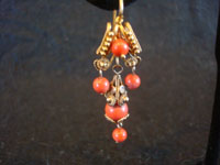 Mexican vintage jewelry, a beautiful pair of gold and coral earrings in a traditional colonial style, c. 1900. Closeup photo of one earring.