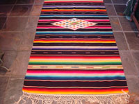 Mexican vintage sarapes and textiles, a lovely Saltillo sarape with a black background, c. 1930's. The sarape has a beautiful center medallion with silk, and the fringe is intact at both ends. Main photo of the saltillo.