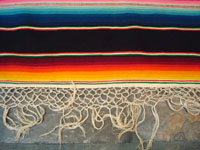 Mexican vintage sarapes and textiles, a lovely Saltillo sarape with a black background, c. 1930's. The sarape has a beautiful center medallion with silk, and the fringe is intact at both ends. Closeup photo of the fringe on one end.