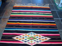 Mexican vintage sarapes and textiles, a lovely Saltillo sarape with a black background, c. 1930's. The sarape has a beautiful center medallion with silk, and the fringe is intact at both ends. Photo showing the top half of the Saltillo sarape.