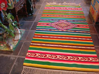 Mexican vintage textiles and sarapes, a stunning Saltillo sarape with silk and real silver threads in the center diamond, c. 1920-30. The decorative end-bars on each side feature lovely rosettes and the fringe is fully intact on each end. Main photo of sarape.