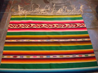 Mexican vintage textiles and sarapes, a stunning Saltillo sarape with silk and real silver threads in the center diamond, c. 1920-30. The decorative end-bars on each side feature lovely rosettes and the fringe is fully intact on each end. Photo of one end of the Saltillo sarape showing fringe intact.