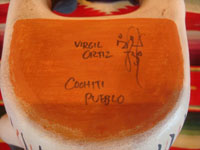 Native American Indian folk art, and Native American Indian pottery and ceramics, a wonderful, very whimsical pottery figure depicting an Anglo or European visitor or clown, signed by the famous artist, Virgil Ortiz, Cochiti Pueblo, c. 1980. Photo showing the bottom of the figure, showing the artist's signature, Virgil Ortiz, Cochiti Pueblo.