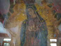Mexican vintage devotional art and Mexican vintage tin-work art, a wonderful nicho with a retablo of Our Lady of Guadalupe; retablo on tin c. 1920. The lovely tin-work nicho is c. 1930-40, with wonderful inverted painting decorating the frame. A closeup photo of the Virgin's face.