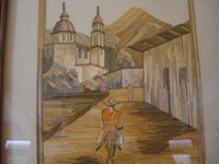 Closeup photo of the straw-art picture of man riding burro through village.