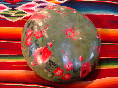 Mexican vintage folk art, a laquer-ware painted gourd from Chiapa de Curso, Chiapas, c. 1930. The gourd is beautifully laquered with a lovely green undercoat, and then is decorated with hand-painted flowers in bright pink hues.